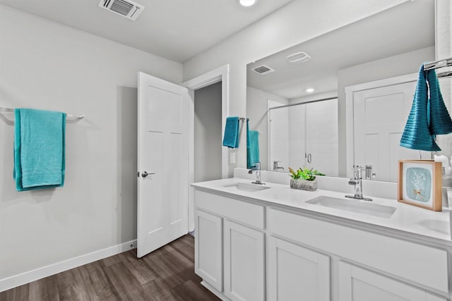 bathroom with hardwood / wood-style floors, vanity, and a shower with shower door