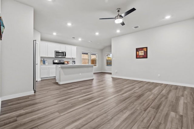 unfurnished living room featuring ceiling fan, sink, and light hardwood / wood-style flooring