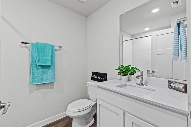 bathroom with hardwood / wood-style flooring, vanity, toilet, and a shower