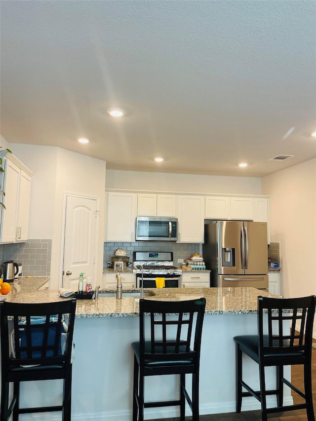 kitchen with decorative backsplash, a breakfast bar, stainless steel appliances, white cabinets, and dark hardwood / wood-style floors