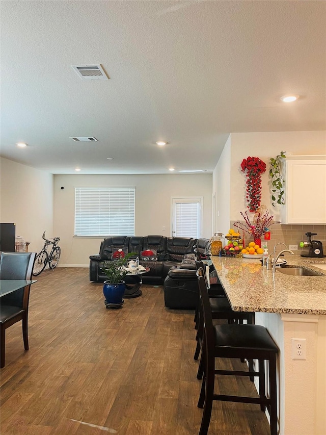 living room featuring a textured ceiling, dark hardwood / wood-style floors, and sink