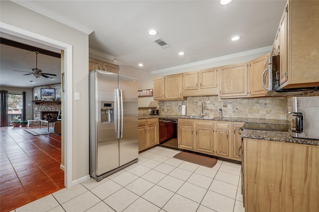 kitchen with a stone fireplace, ceiling fan, light tile patterned floors, tasteful backsplash, and stainless steel appliances