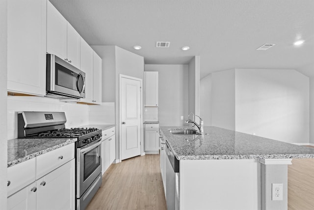 kitchen featuring a kitchen island with sink, sink, white cabinets, and appliances with stainless steel finishes