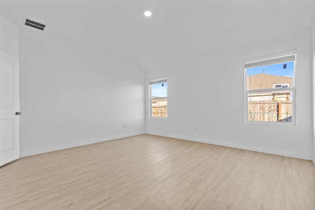 unfurnished room with lofted ceiling, a healthy amount of sunlight, and light hardwood / wood-style floors