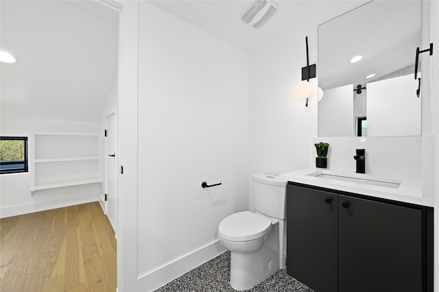 bathroom featuring hardwood / wood-style floors, vanity, vaulted ceiling, toilet, and built in features