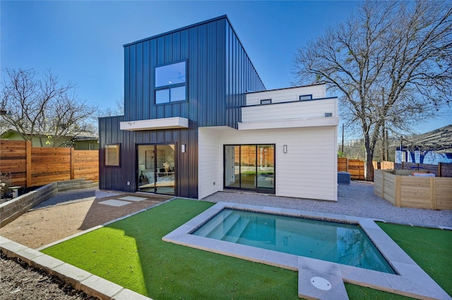 back of house with a fenced in pool and a lawn