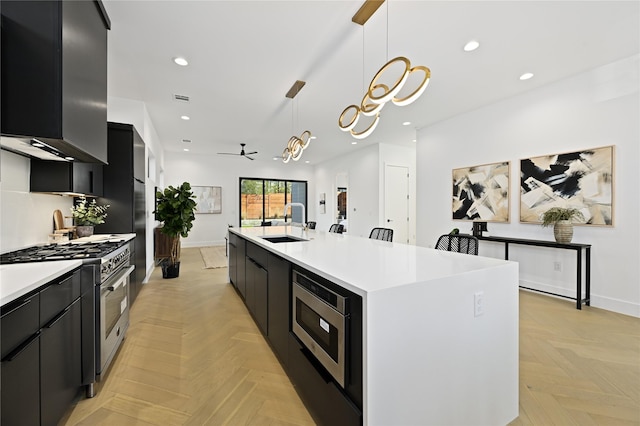 kitchen featuring ceiling fan, pendant lighting, a kitchen island with sink, light parquet flooring, and appliances with stainless steel finishes