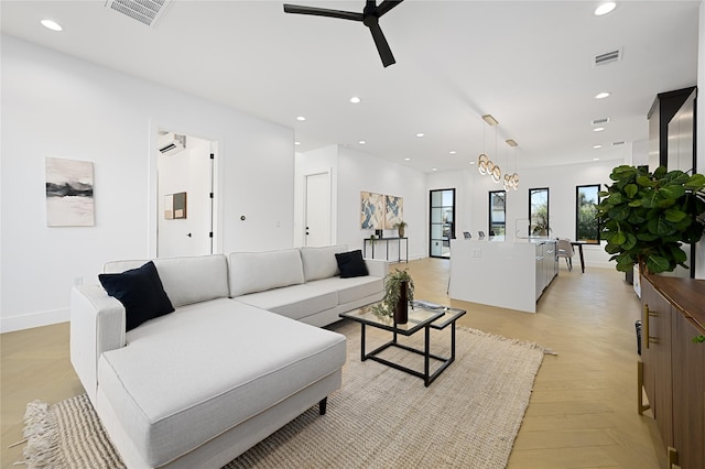 living room with a wall mounted AC and ceiling fan with notable chandelier