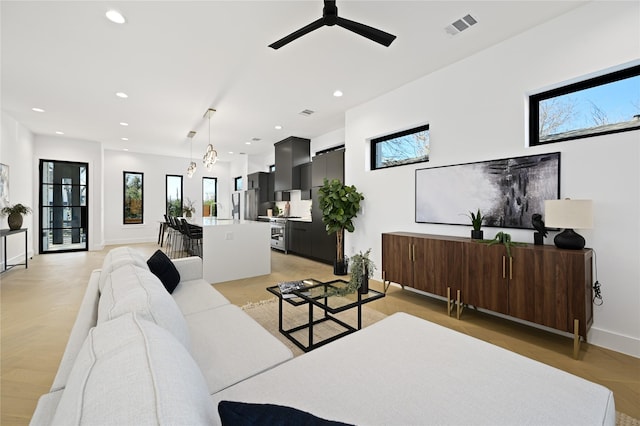 living room featuring ceiling fan with notable chandelier and light parquet floors