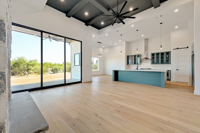 kitchen featuring white cabinetry, a large island, hanging light fixtures, a barn door, and a towering ceiling