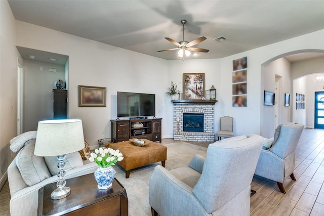 living room featuring a fireplace, light hardwood / wood-style flooring, and ceiling fan