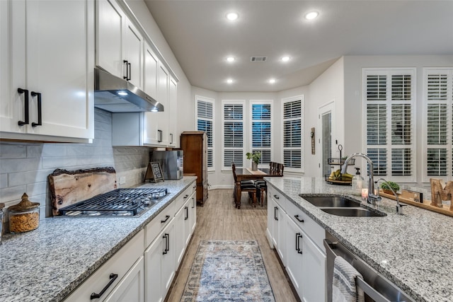 kitchen featuring white cabinetry, sink, stainless steel appliances, light stone counters, and light hardwood / wood-style floors