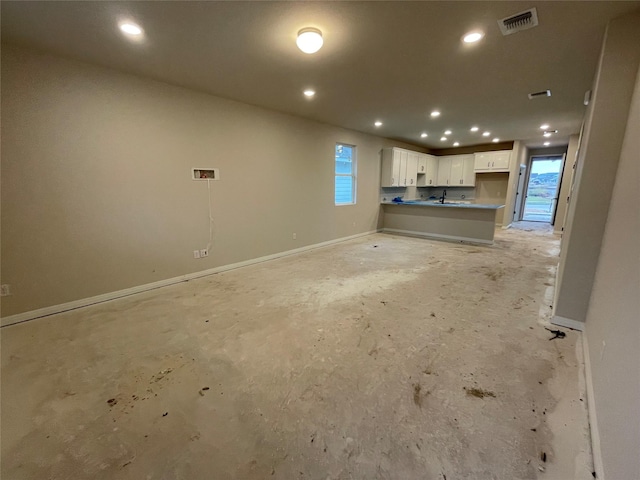 unfurnished living room featuring a wealth of natural light and sink