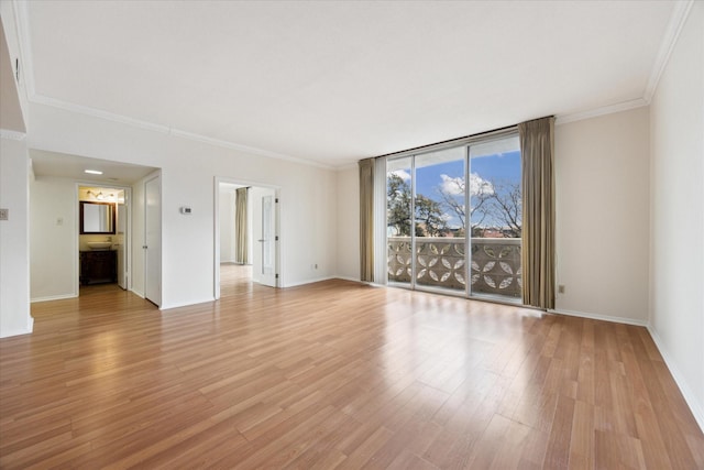 empty room with floor to ceiling windows, crown molding, and light hardwood / wood-style floors