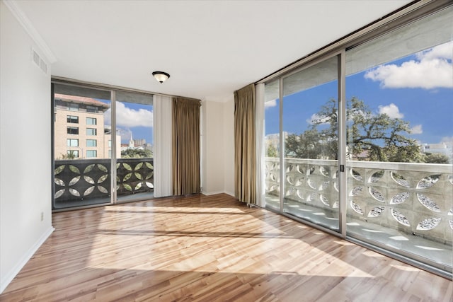 empty room featuring hardwood / wood-style floors, a wall of windows, and crown molding