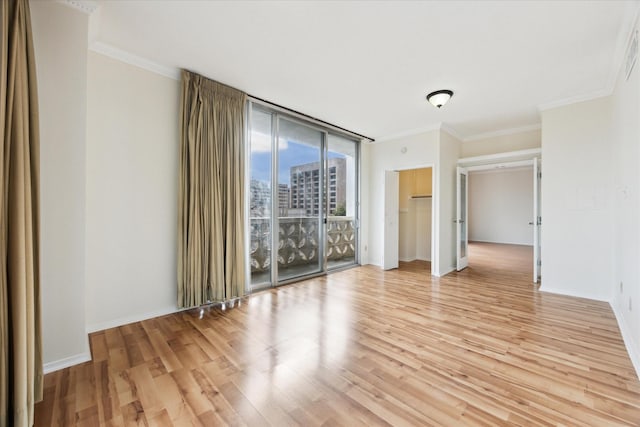 spare room with floor to ceiling windows, light hardwood / wood-style floors, and crown molding