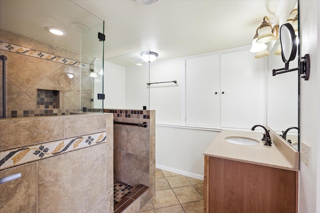 bathroom with tile patterned flooring, a tile shower, and vanity