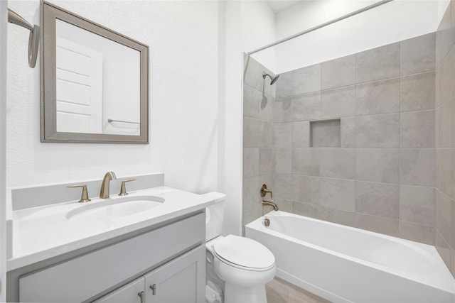 full bathroom featuring vanity, tiled shower / bath combo, and toilet