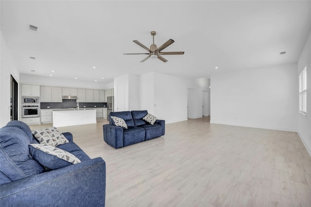 living room featuring ceiling fan and sink