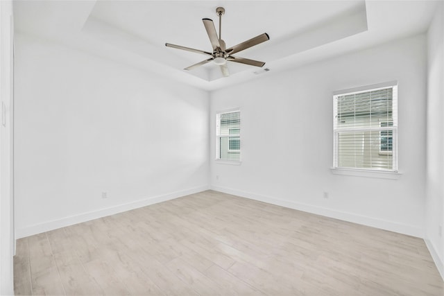 unfurnished room featuring light hardwood / wood-style floors and a raised ceiling