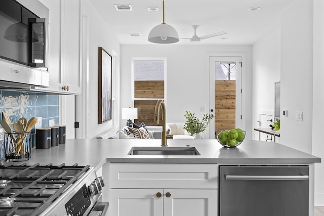 kitchen with sink, stainless steel appliances, white cabinets, decorative light fixtures, and ceiling fan