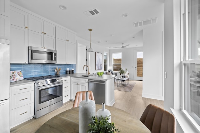 kitchen with stainless steel appliances, light wood-type flooring, ceiling fan, pendant lighting, and white cabinetry