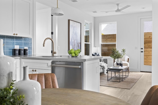 kitchen featuring sink, white cabinetry, dishwasher, light wood-type flooring, and decorative backsplash