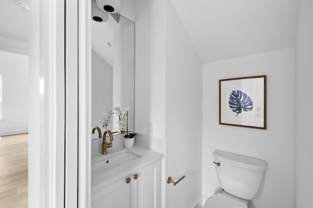 bathroom with toilet, vaulted ceiling, and vanity