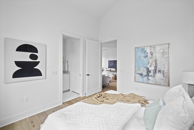 bedroom with high vaulted ceiling, light hardwood / wood-style flooring, and ensuite bath