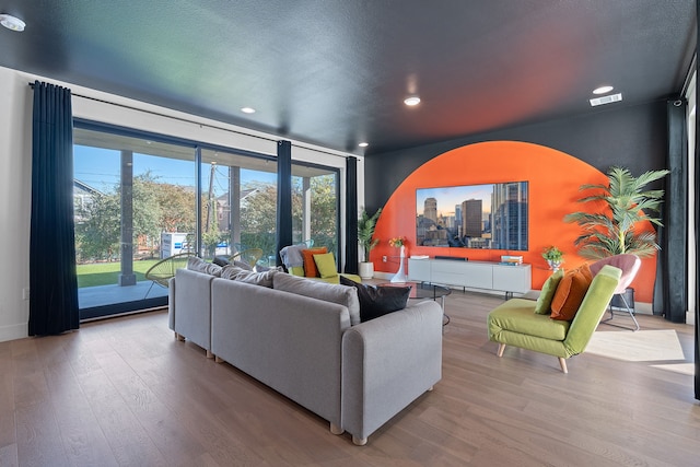 living room with light wood-type flooring and a textured ceiling