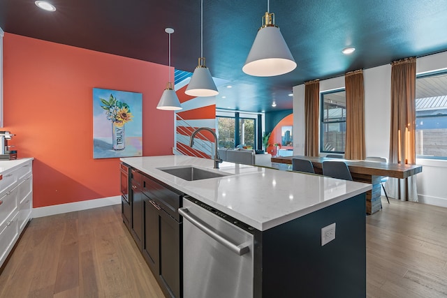 kitchen with sink, a center island with sink, dishwasher, light hardwood / wood-style floors, and hanging light fixtures