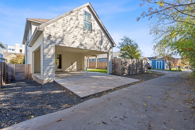 back of house with a carport and a storage unit