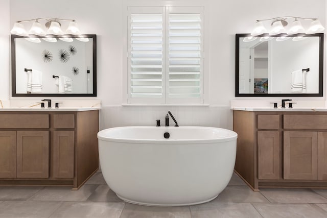 bathroom with a washtub, vanity, and tile patterned flooring