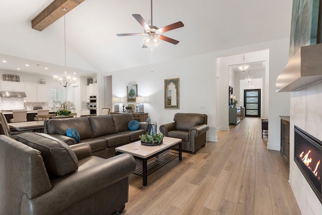 living room with a fireplace, beam ceiling, light wood-type flooring, high vaulted ceiling, and ceiling fan with notable chandelier