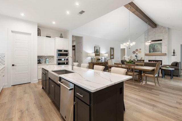 kitchen featuring decorative backsplash, sink, a tiled fireplace, appliances with stainless steel finishes, and white cabinets