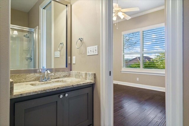 full bathroom with a stall shower, baseboards, wood finished floors, vanity, and ornamental molding