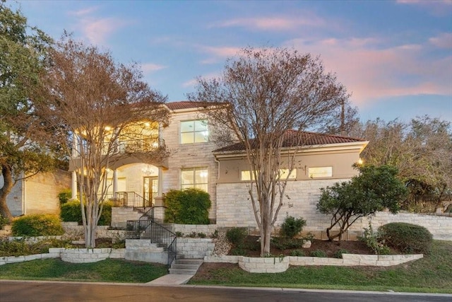 view of front of home featuring stairway, a tile roof, stone siding, and stucco siding