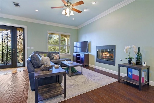 living room featuring a ceiling fan, wood finished floors, a glass covered fireplace, baseboards, and visible vents