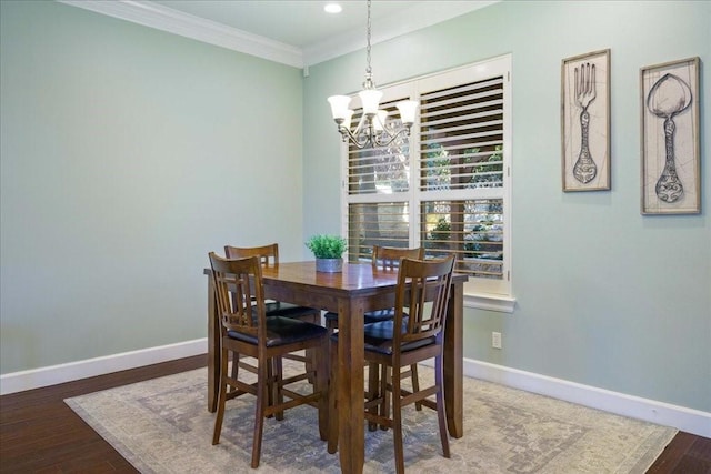 dining room with wood finished floors, baseboards, ornamental molding, and an inviting chandelier