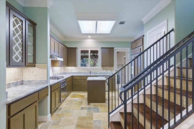 9 Sunset Park Cv, Lakeway, TX 78734 - kitchen featuring appliances with stainless steel finishes, backsplash, ornamental molding, under cabinet range hood, and light stone countertops