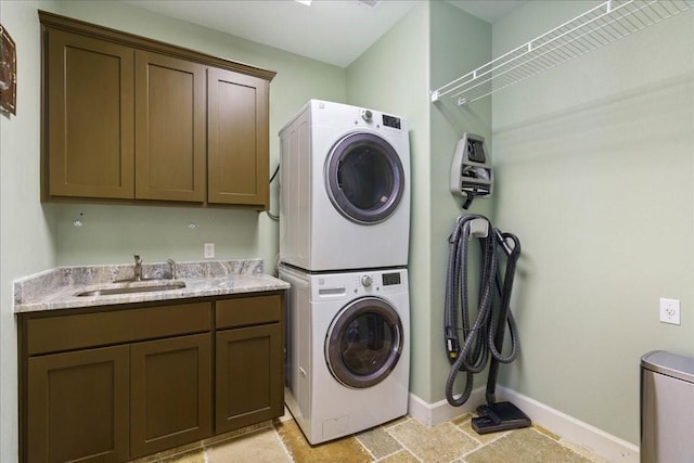 washroom featuring sink, cabinets, and stacked washer / dryer