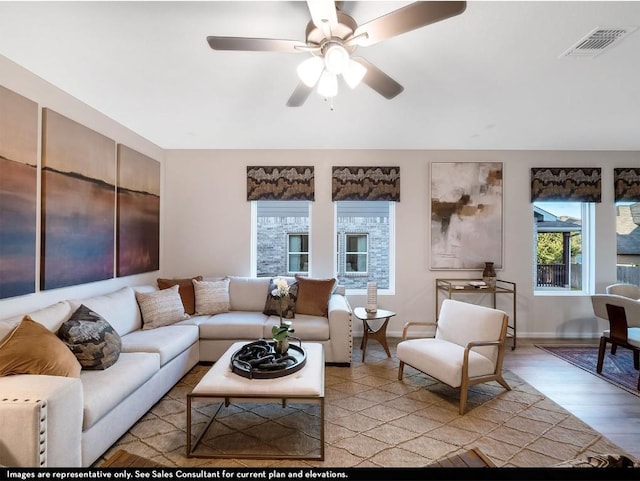living room with a ceiling fan, visible vents, light wood-style flooring, and baseboards