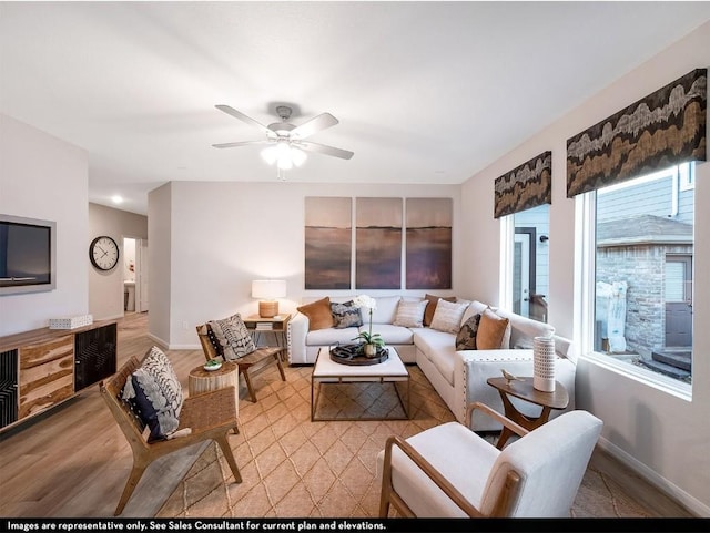 living area with baseboards, ceiling fan, and light wood finished floors
