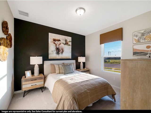 carpeted bedroom with an accent wall, visible vents, and baseboards