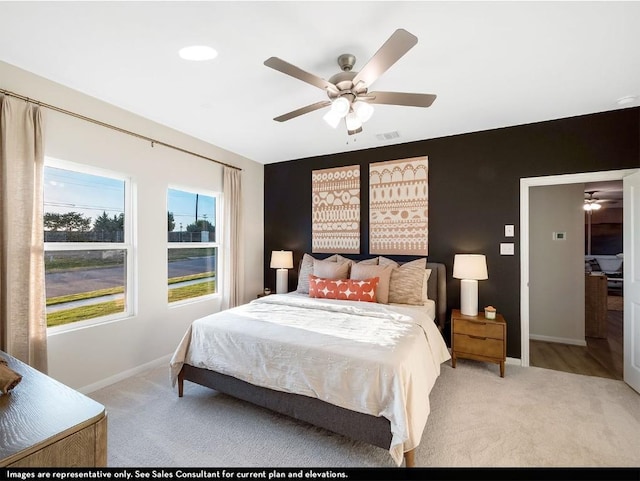 bedroom featuring a ceiling fan, visible vents, light colored carpet, and baseboards