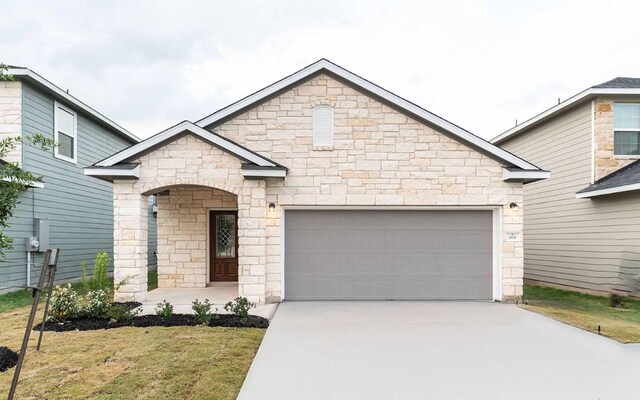 view of front of property featuring a garage, a front lawn, concrete driveway, and stone siding