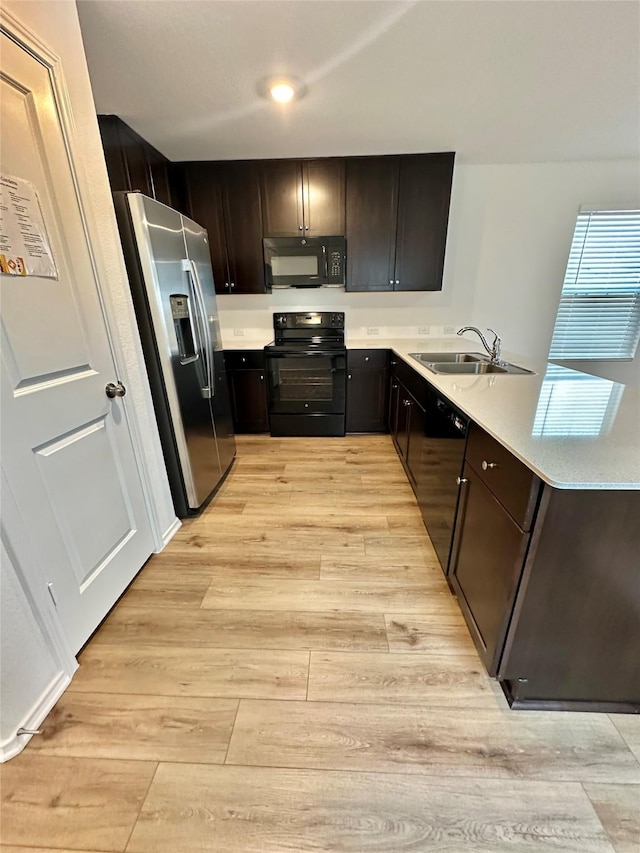 kitchen with kitchen peninsula, light wood-type flooring, dark brown cabinets, sink, and black appliances