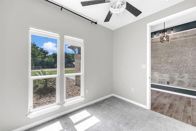 empty room featuring ceiling fan with notable chandelier and carpet floors