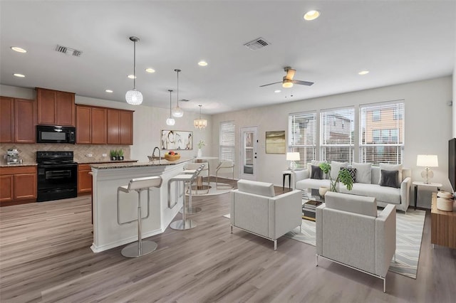 living area featuring light wood-style flooring, recessed lighting, ceiling fan, and visible vents