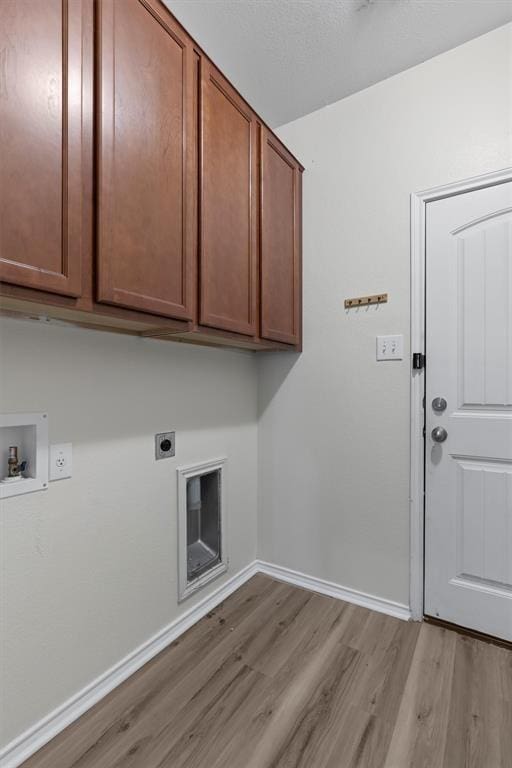 clothes washing area featuring hookup for an electric dryer, light hardwood / wood-style floors, cabinets, and washer hookup